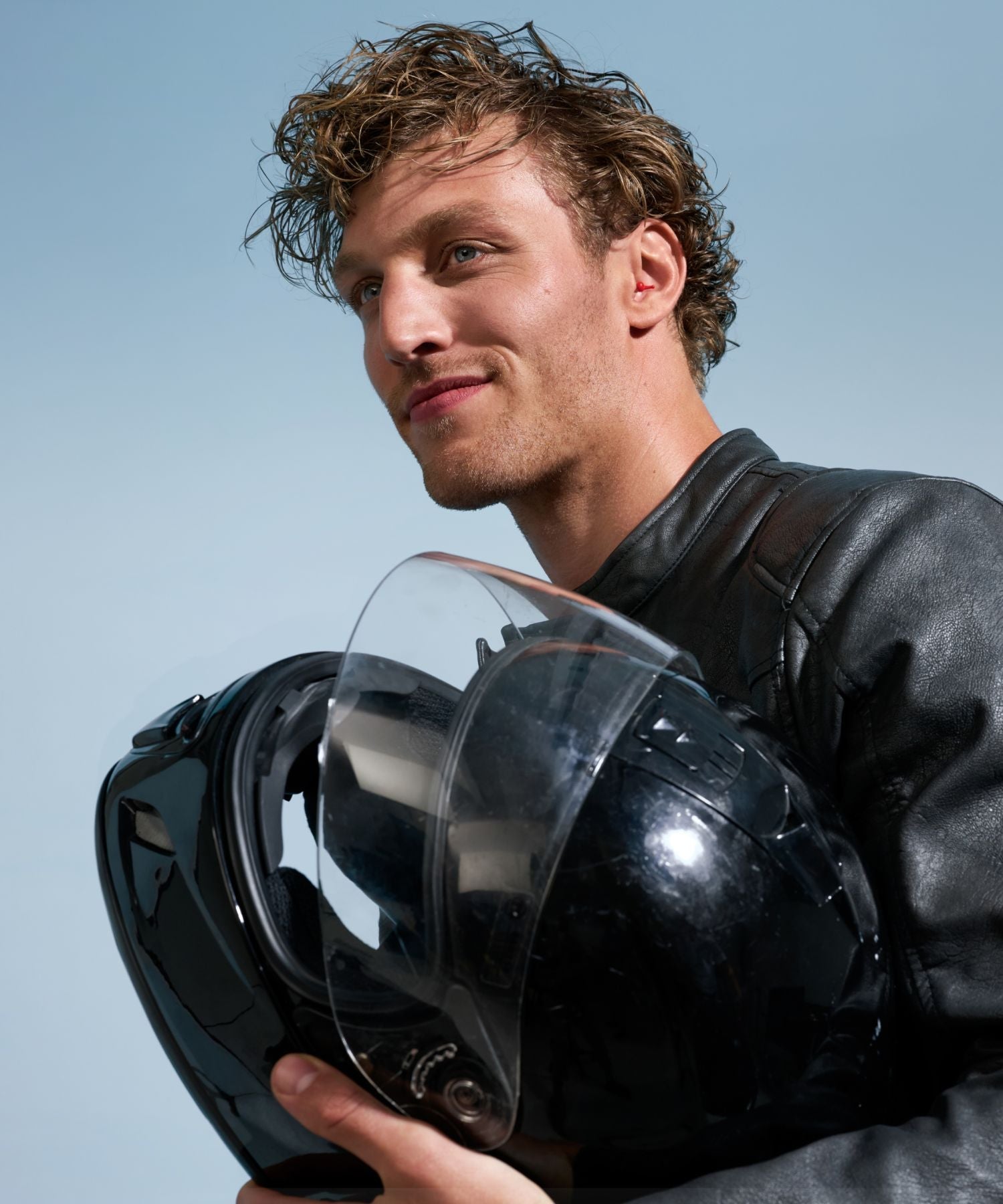 Een man met een motorhelm die Alpine MotoSafe-oordoppen draagt.