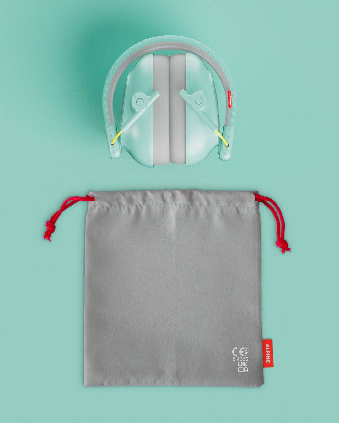 Alpine Muffy Baby ear defenders in mint, folded, with grey carrying pouch 
