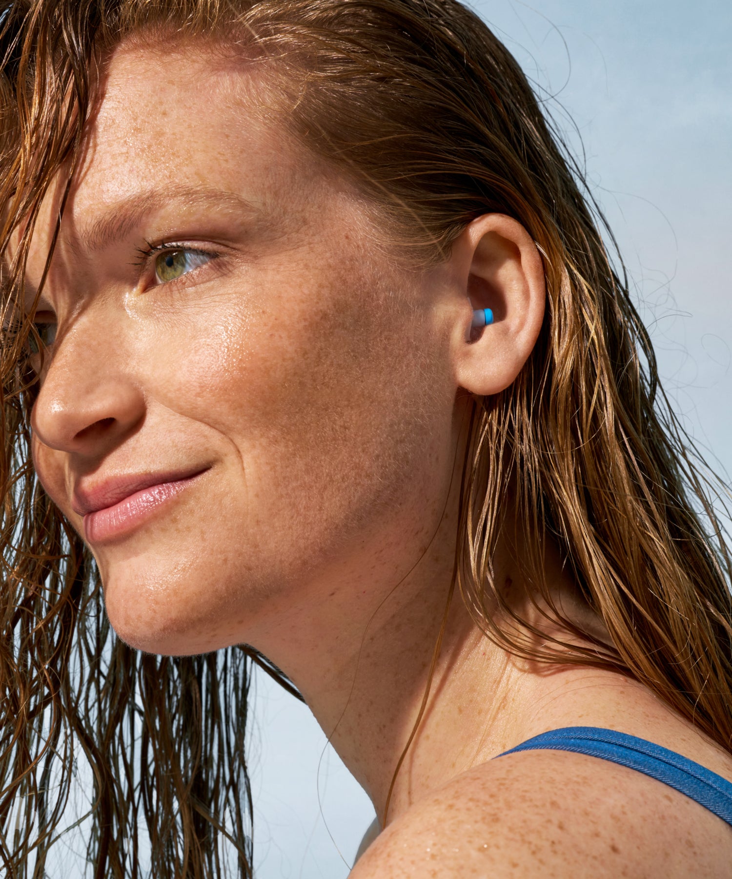 Alpine SwimSafe earplug worn by a woman with wet hair in a swimsuit 